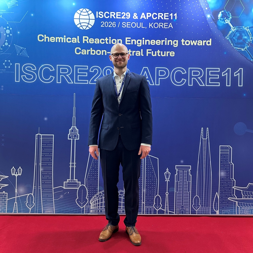 Mann im Anzug vor einer blauen Konferenzwand der ISCRE29 & APCRE11 in Seoul, Korea.